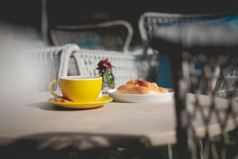 Photo d'une terrasse vide avec un tasse de cappuccino et un croissant sur une table