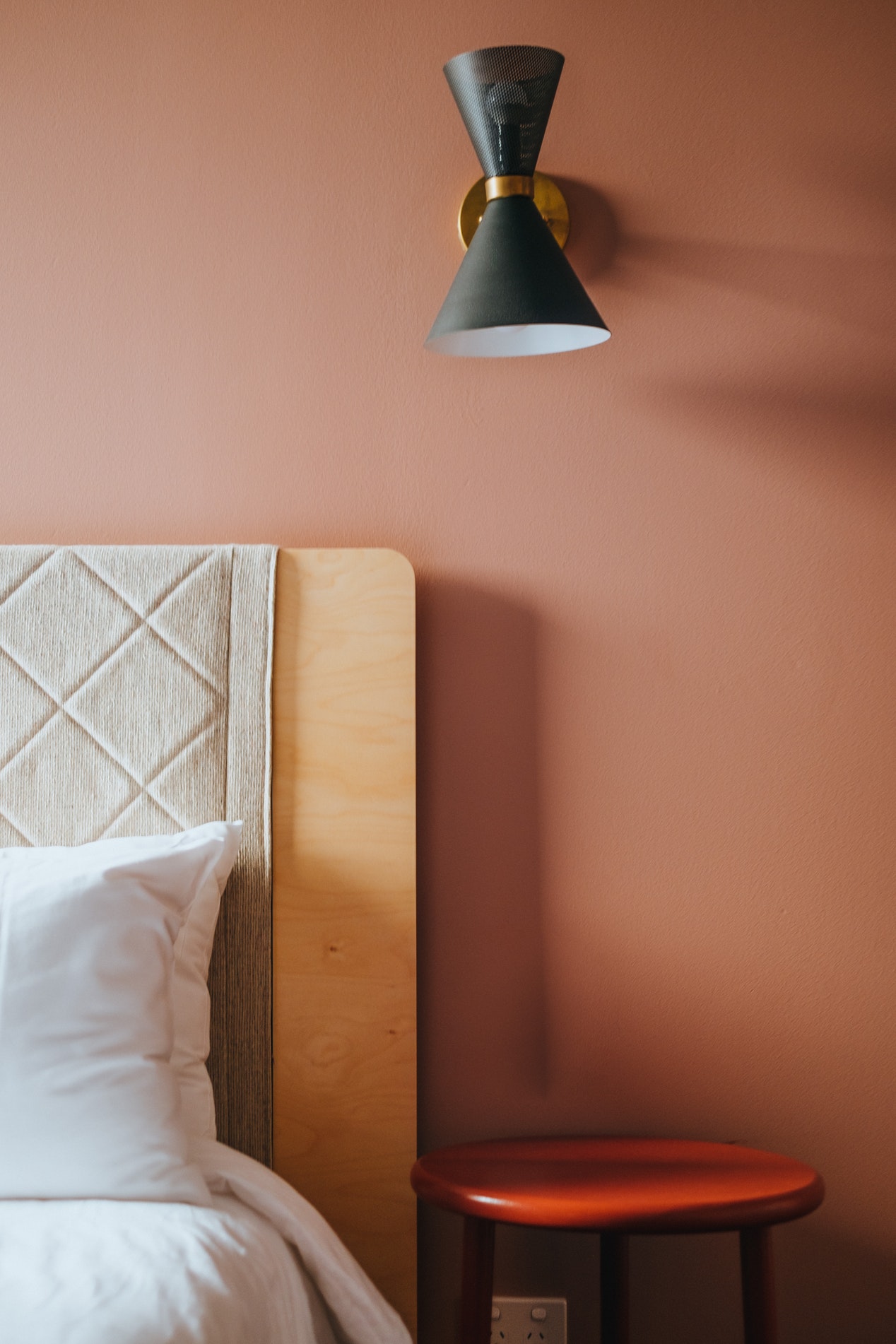 Décoration d'architecte d'intérieur d'une chambre adulte: Une lampe murale au dessus de la table de chevet à côté du lit.